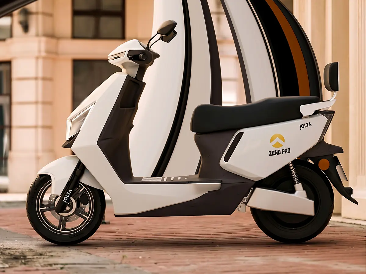 Jolta Zeno Pro electric scooty in white on a brick street, under a sweeping striped arch